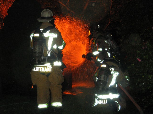 The nozzle being opened as the attack begins on a swimming pool motor that is on fire.